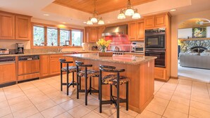 A spacious kitchen with wooden cabinets, a large island with bar stools, and modern appliances.