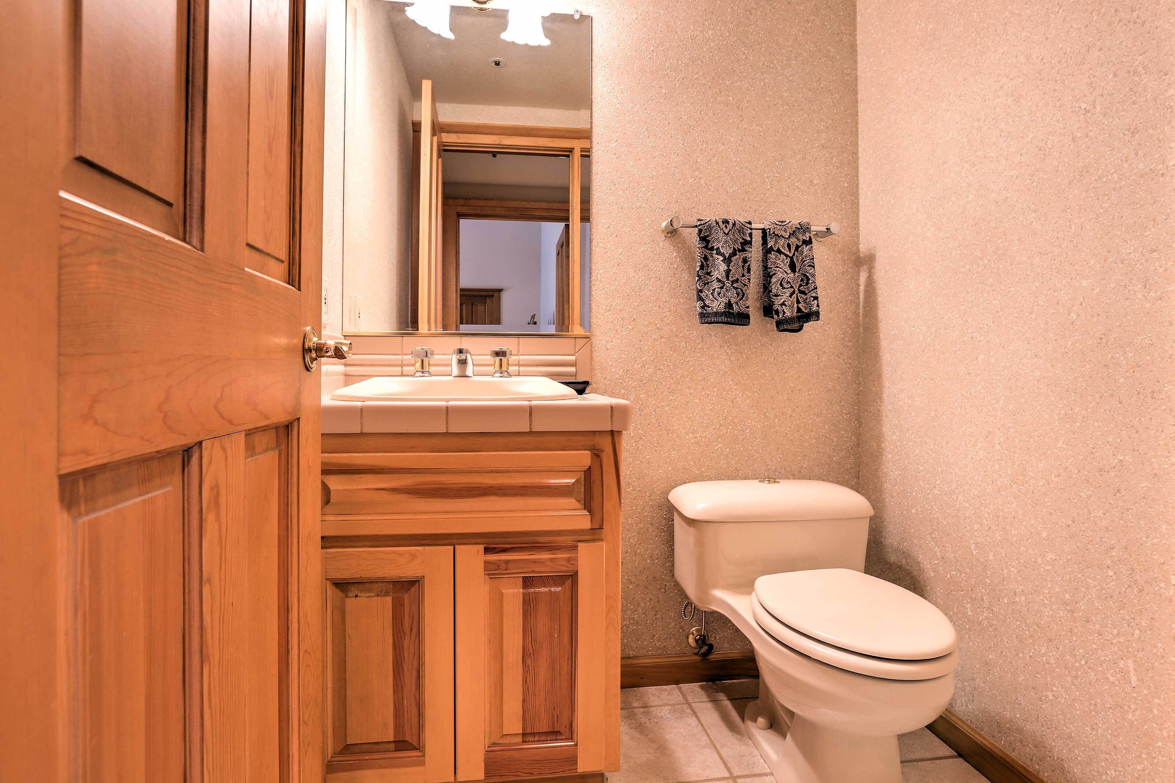 A bathroom with wooden cabinets, a sink, a toilet, and a towel rack with patterned towels.