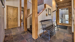 Un escalier en bois avec un banc, un tapis à motifs et une grande fenêtre.