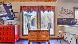 Un coin repas avec une table et des chaises en bois, un buffet rouge et un téléviseur posé sur un meuble.