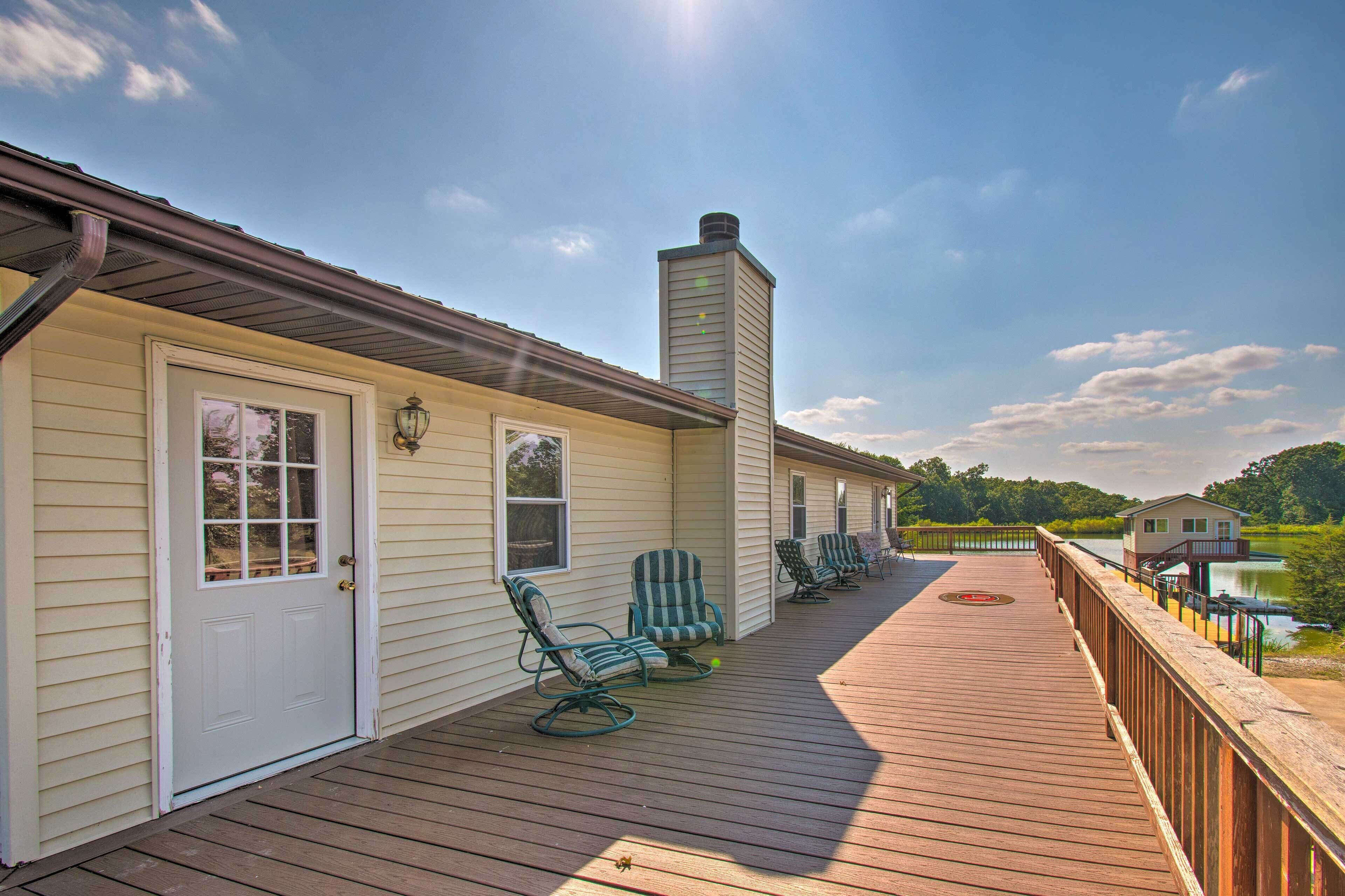 A wooden deck with outdoor seating and a view of a lake.