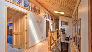 Een hal met houten vloeren, een trap en een deur naar een kamer met een blauw beddegoed.