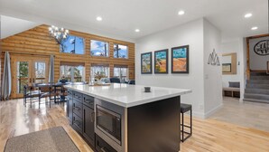 A modern kitchen with a large island, wooden accents, and large windows offering views of the outdoors. - Spacious Mtn Manor, 1 Mi to Brian Head Resort! (Brian Head)