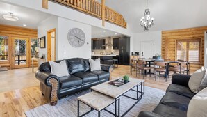 A spacious living area with a black leather sofa, a wooden coffee table, and a dining area with wooden chairs and a table. - Spacious Mtn Manor, 1 Mi to Brian Head Resort! (Brian Head)