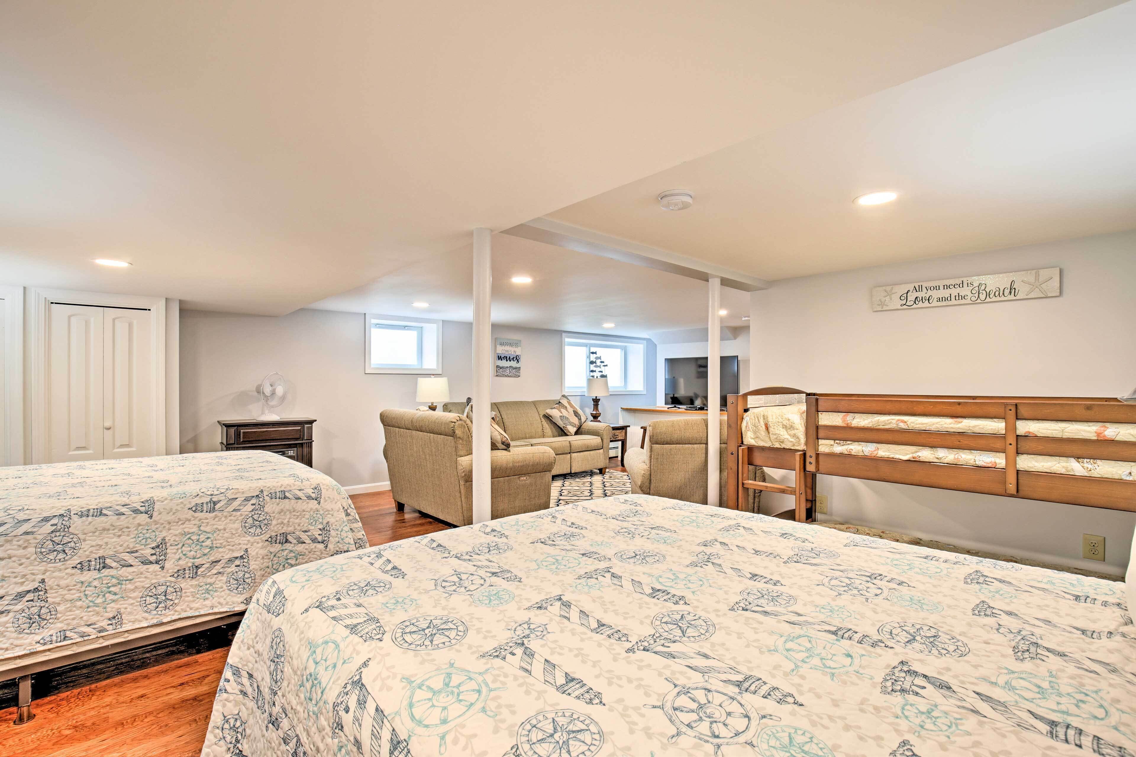 A bedroom with two beds, a wooden headboard, a sofa, and a desk.