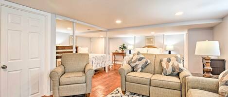A living room with two armchairs, a sofa, a patterned rug, and a wooden floor.