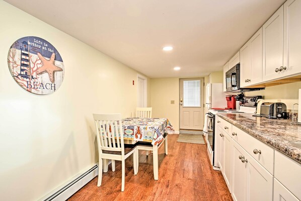 A kitchen with white cabinets, a microwave, and a coffee maker.