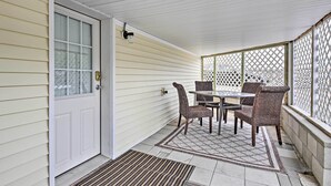 A covered porch with a white door, a table with four chairs, and a lattice screen. - Old Orchard Beach Home w/ Patio: Walk to Beach (Old Orchard Beach)