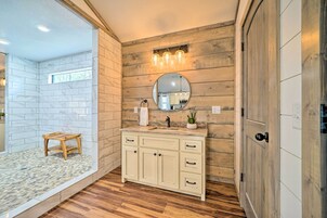 Un baño con tocador de madera, un espejo redondo y un taburete pequeño.