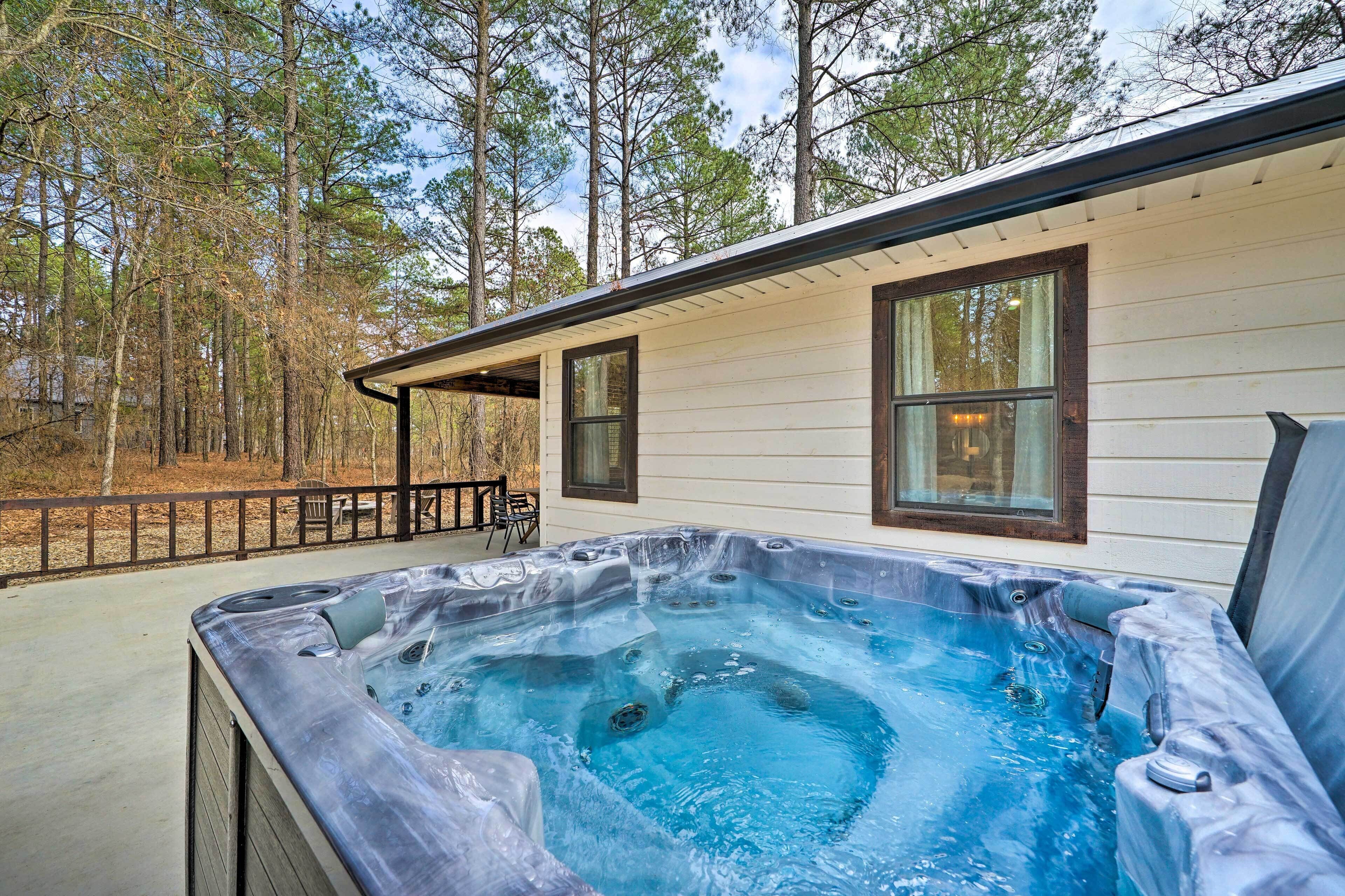 A hot tub in a backyard with a wooden deck and a house in the background.