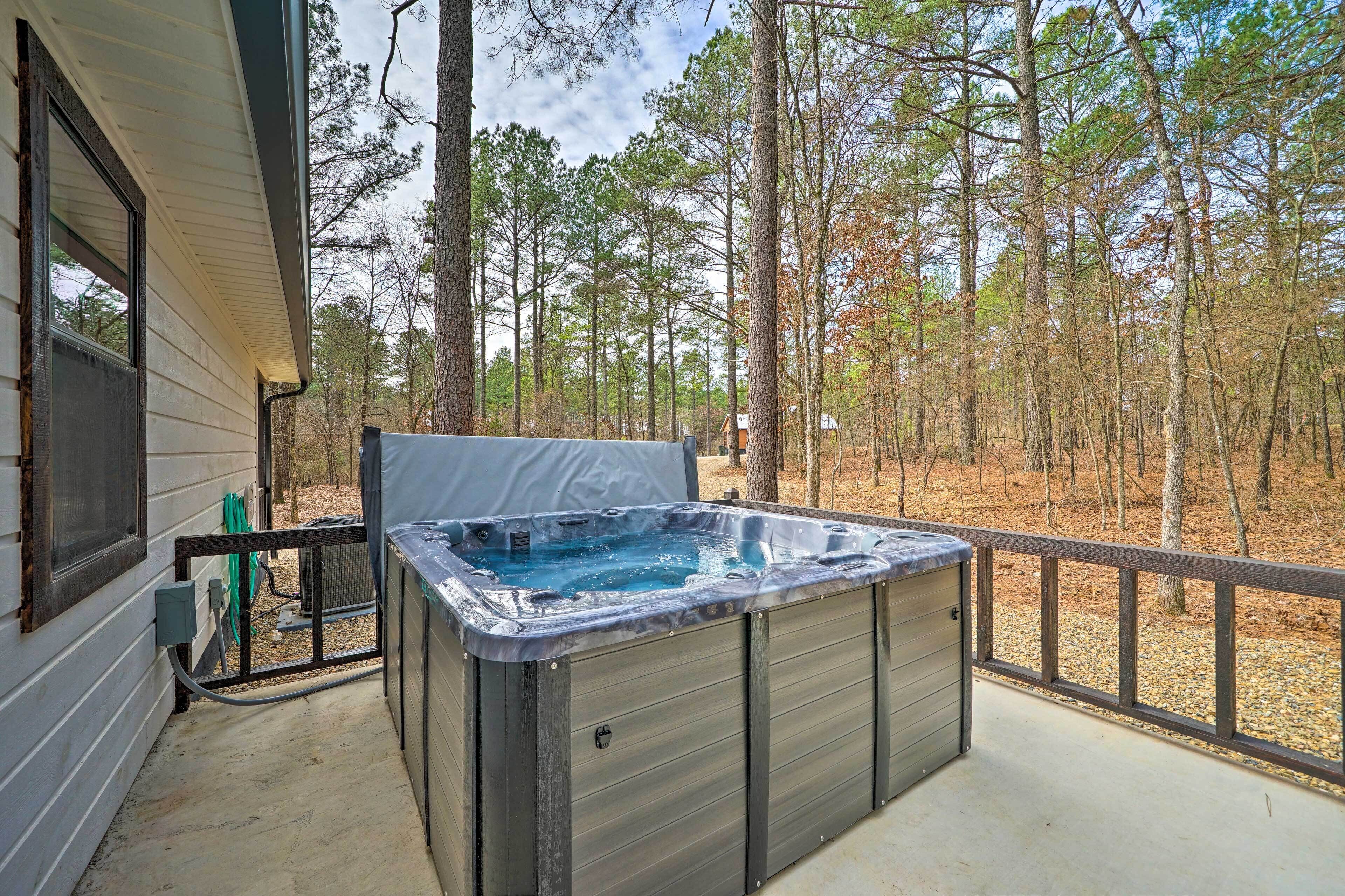 A hot tub on a covered deck with a view of a wooded area.