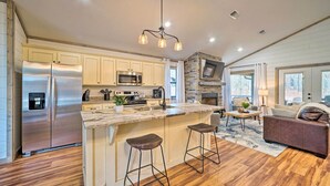 Une cuisine moderne dotée d’un grand îlot central, d’appareils électroménagers en acier inoxydable et d’un mur décoratif en pierre.