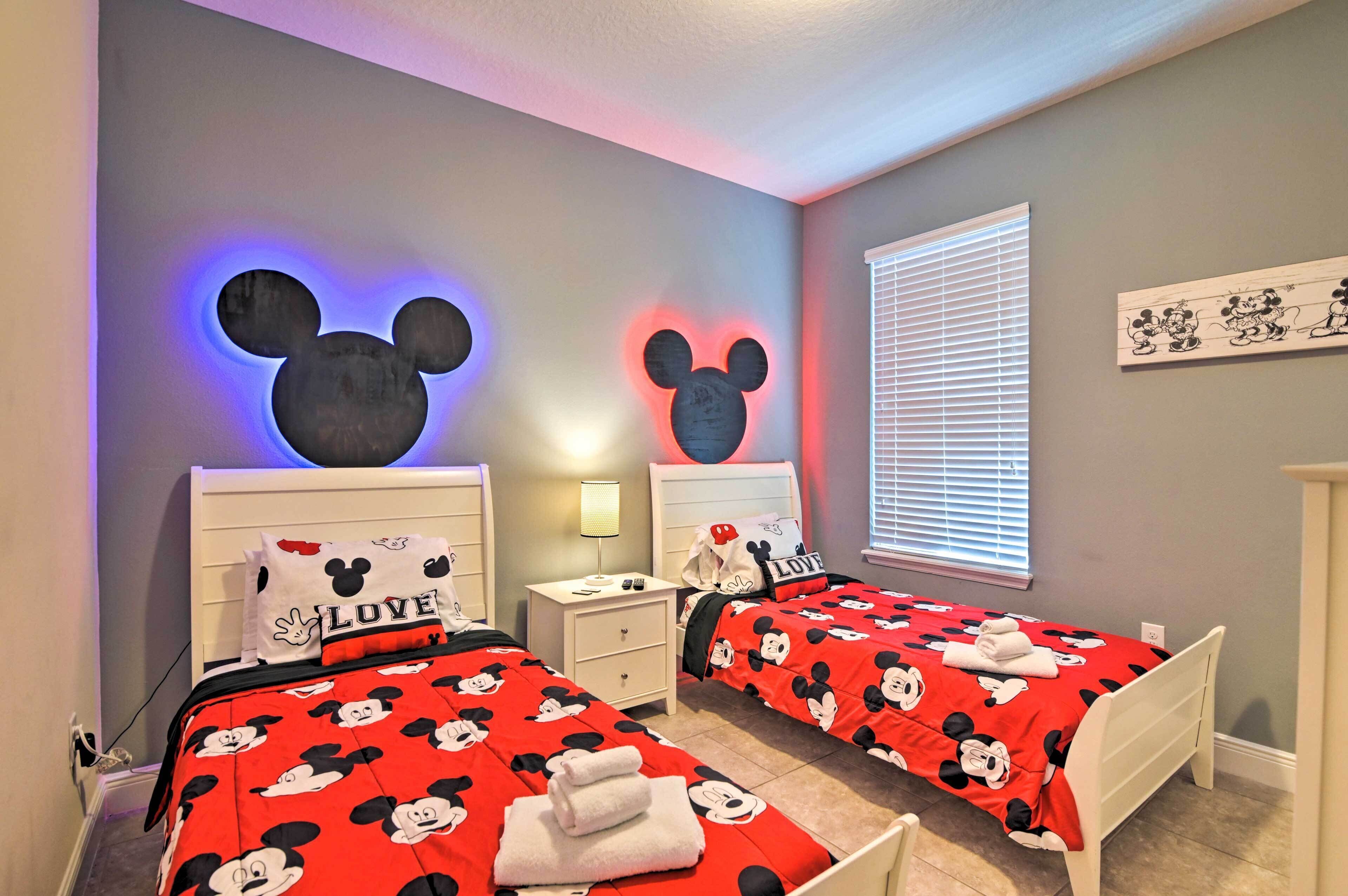 Ein Schlafzimmer mit zwei Betten, jeweils mit Bettwäsche und Kopfstützen im Mickey-Mouse-Design.