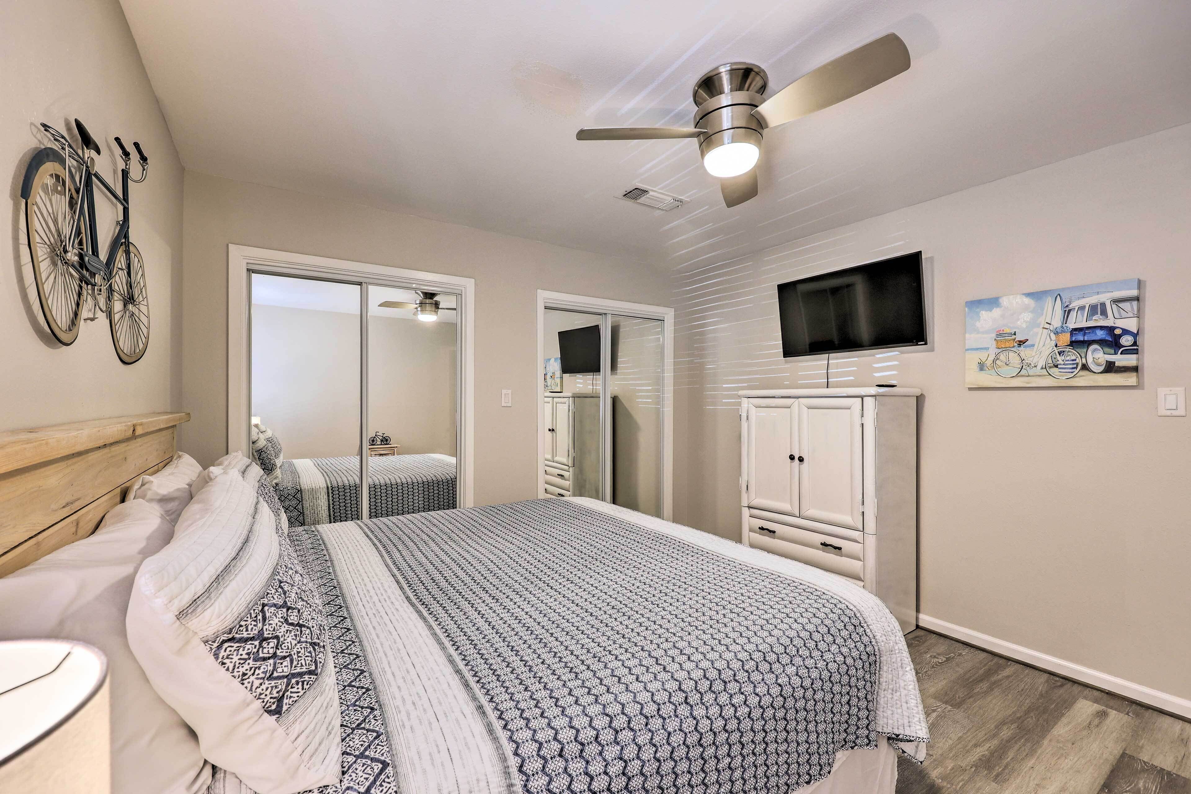 A bedroom with a bed, a ceiling fan, a TV, and a bicycle mounted on the wall.