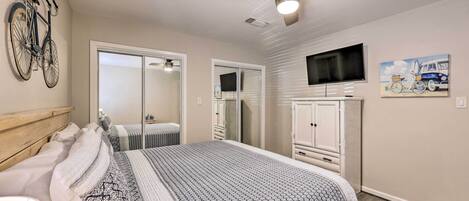 A bedroom with a bed, a ceiling fan, a TV, and a bicycle mounted on the wall.