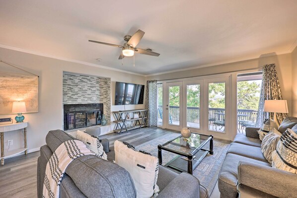 A living room with a sofa, coffee table, TV, fireplace, and a balcony with outdoor furniture. - Hot Tub Access: Fantastic Condo in Hot Springs! (Hot Springs)