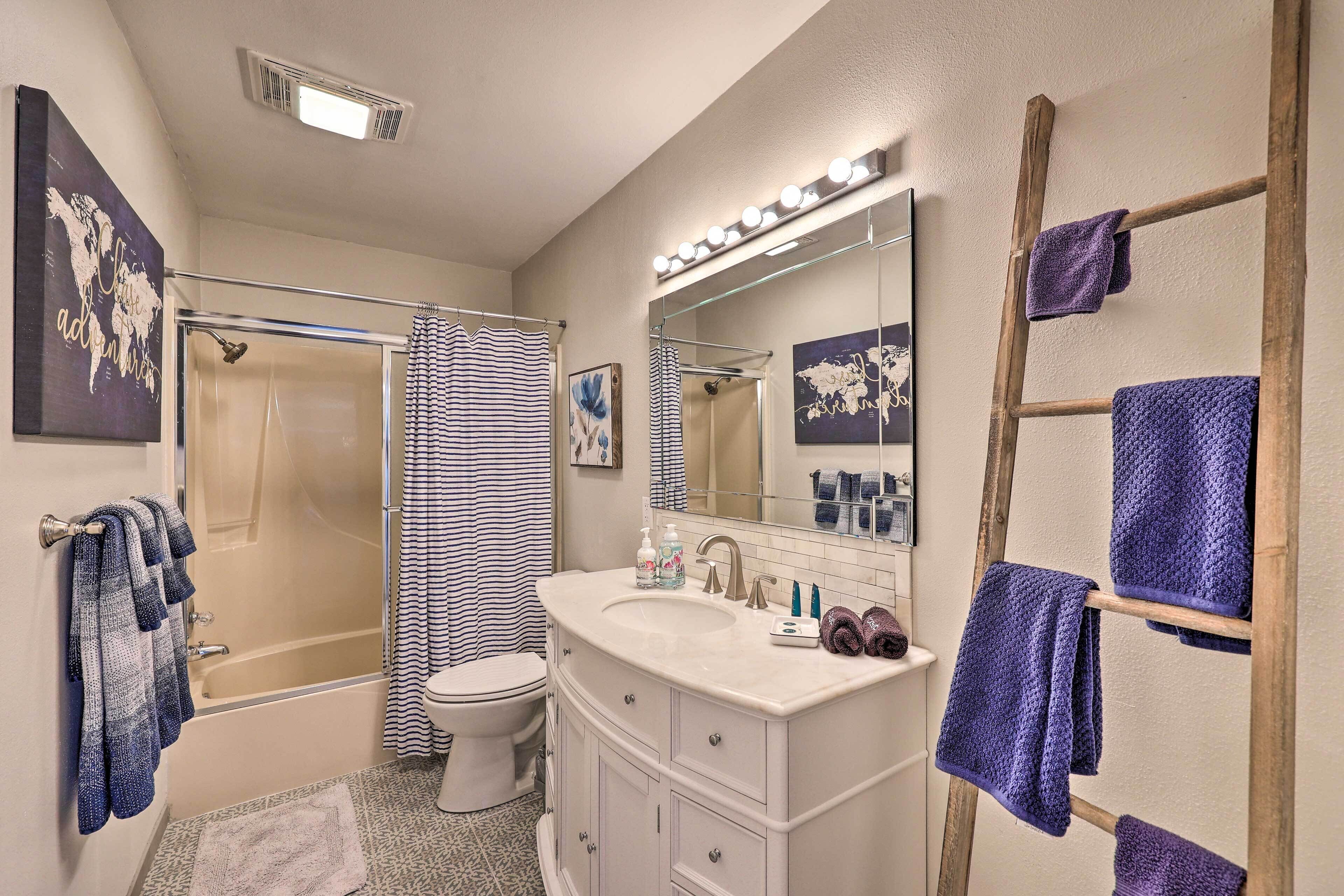 A bathroom with a bathtub, toilet, and sink. There are towels hanging on a rack and a mirror above the sink.
