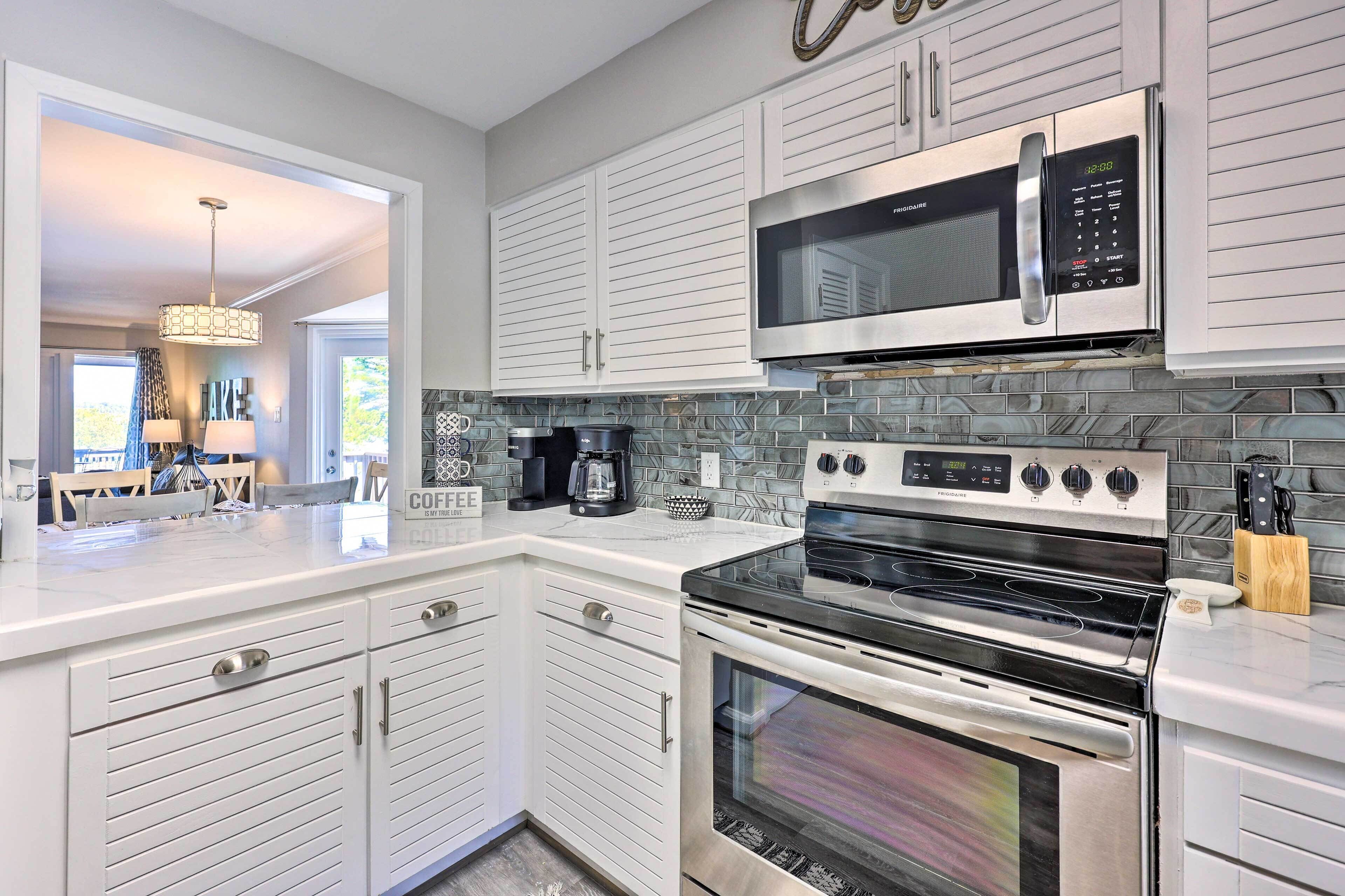 A modern kitchen with white cabinetry, a stainless steel microwave, a double oven, and a tiled backsplash.