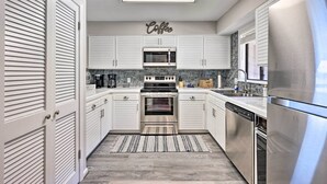 Una cocina moderna con armarios blancos, electrodomésticos de acero inoxidable y un letrero que dice 'Coffee'.
