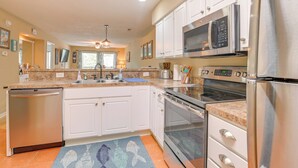 A modern kitchen with white cabinets, stainless steel appliances, and a granite countertop. - Pawleys Island Vacation Rental on Golf Course! (Pawleys Island)