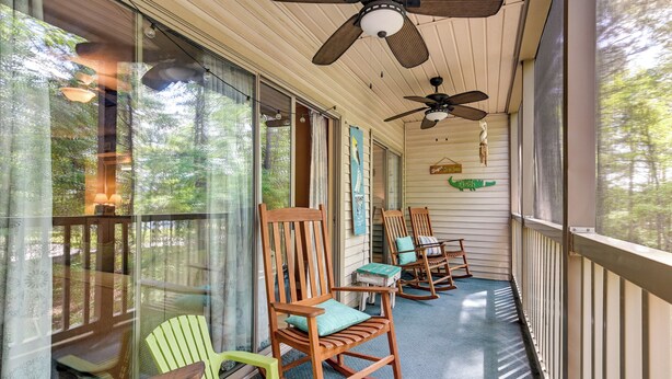 A covered porch with rocking chairs and a ceiling fan. - Pawleys Island Vacation Rental on Golf Course! (Pawleys Island)