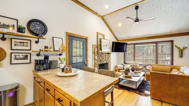 A spacious living area with a large wooden dining table, a cozy sofa, and a fireplace. - Boone Hideaway w/ Deck, Grill & Hot Tub! (Boone)