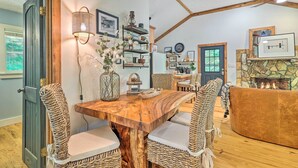 A rustic interior with a wooden dining table, woven chairs, a stone fireplace, and a ceiling fan. - Boone Hideaway w/ Deck, Grill & Hot Tub! (Boone)