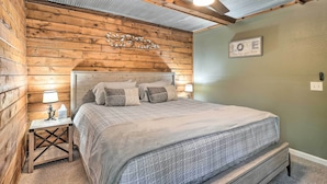 Ein Schlafzimmer mit Holzwandverkleidung, einem Bett, einem Nachttisch und einem Deckenventilator.
