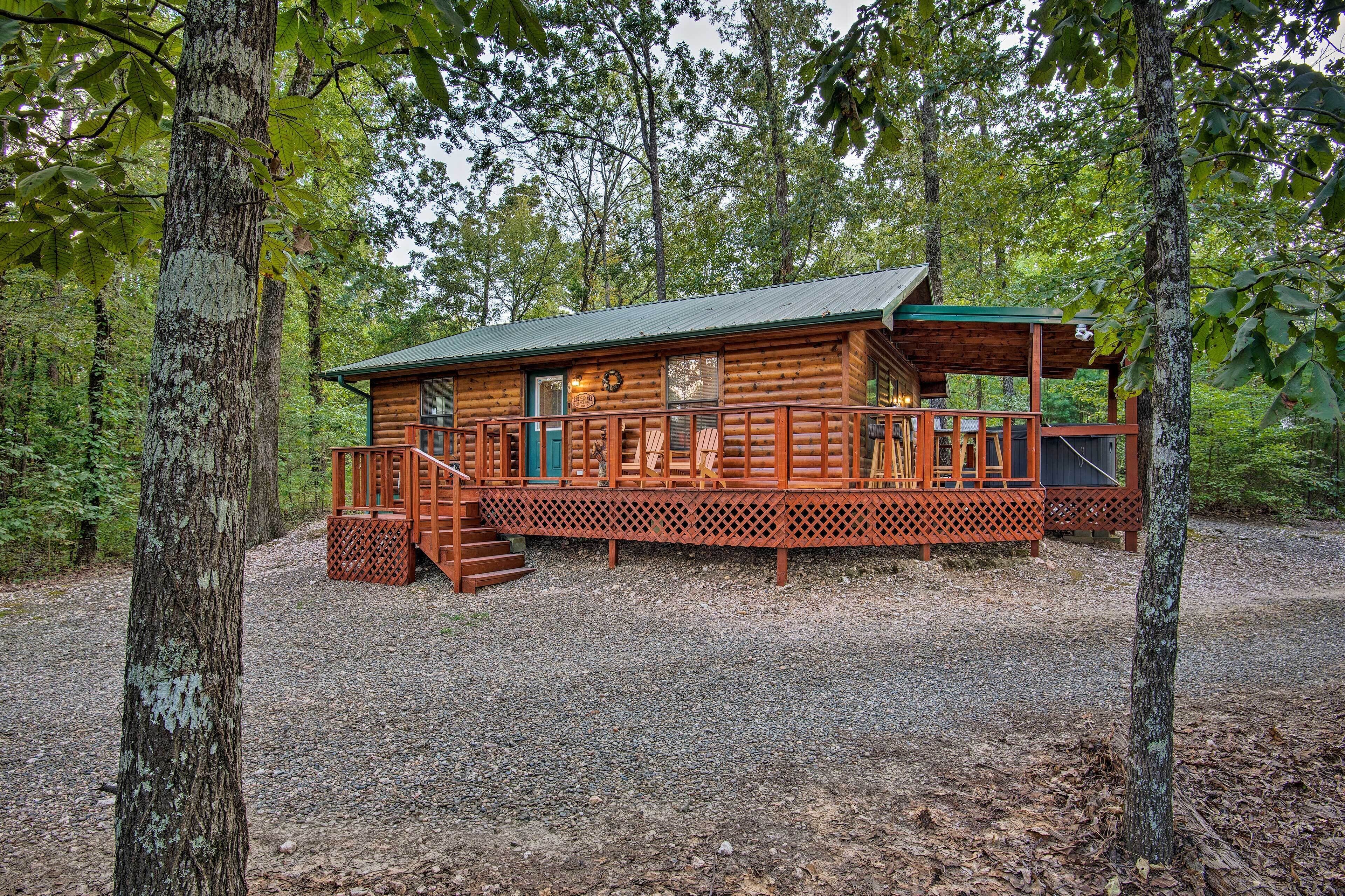 Une cabane en bois avec un porche, entourée d’arbres.