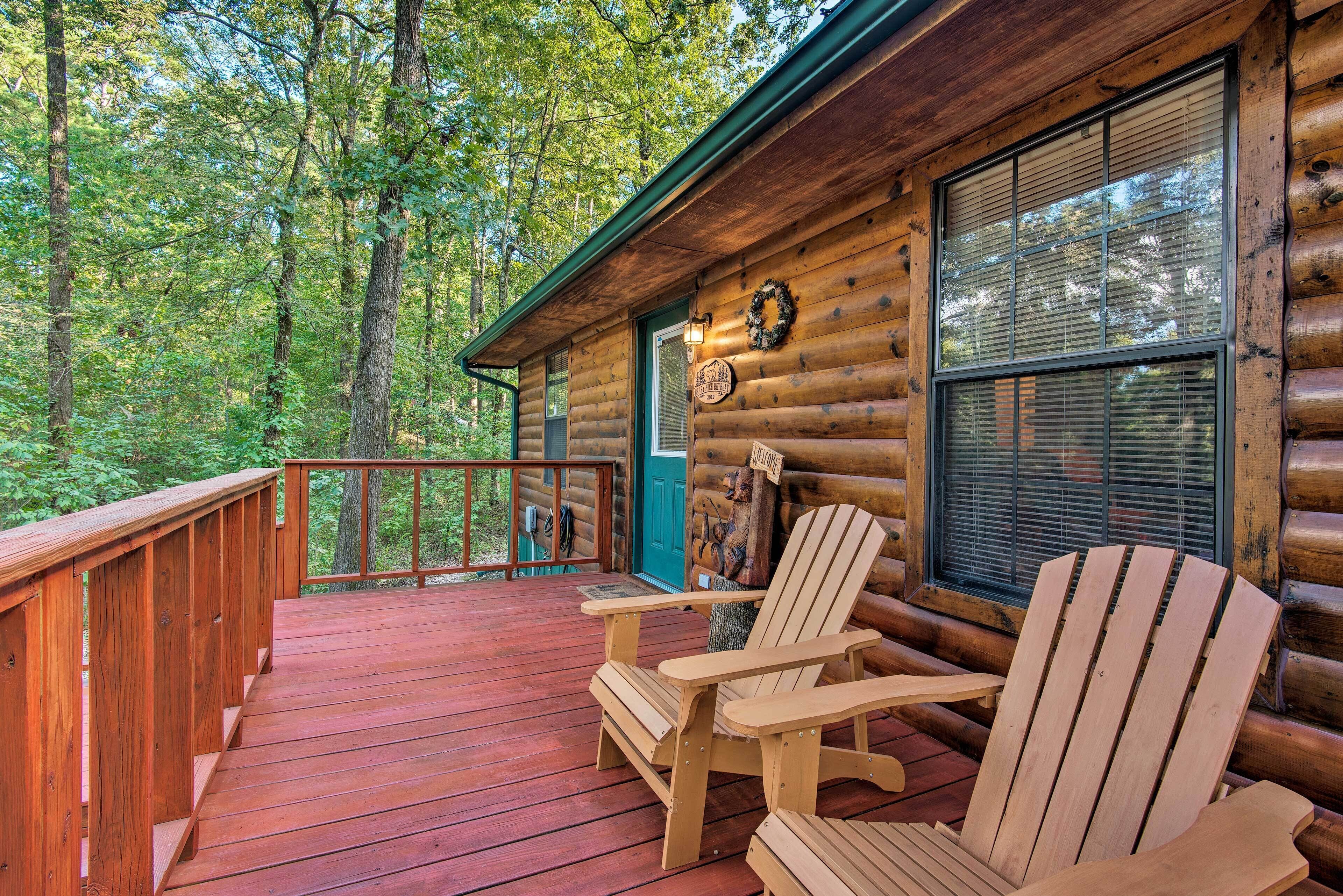 A wooden cabin with a deck, two Adirondack chairs, and a door with a wreath.
