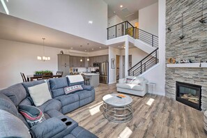 A spacious living area with a gray sectional sofa, a round coffee table, and a stone fireplace. - Inviting Hideout Townhome w/ Balcony & Lake Views! (Heber City)