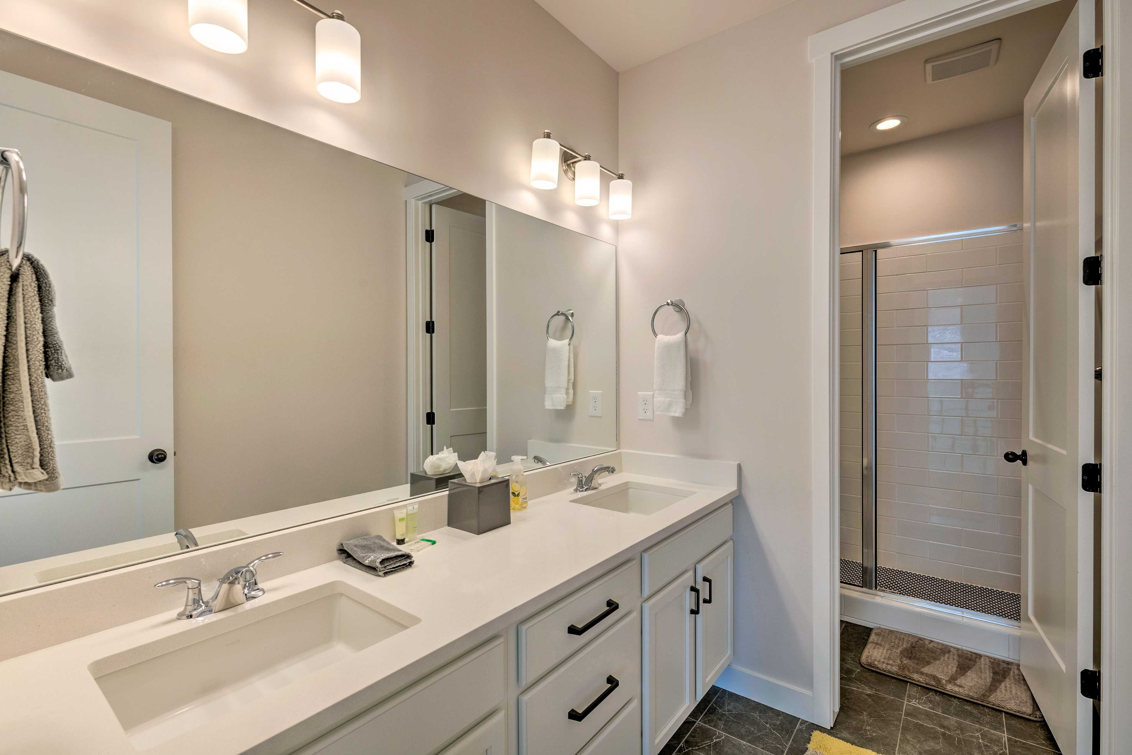 A modern bathroom with two sinks, a large mirror, and a glass shower enclosure.