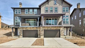 A two-story house with a stone facade, two garage doors, and a balcony. - Inviting Hideout Townhome w/ Balcony & Lake Views! (Heber City)