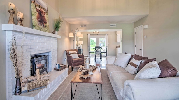 A living room with a fireplace, a sofa, a coffee table, and a dining area in the background. - Relaxing Townhome, 4 Mi to Mizzou University! (Columbia)