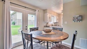 A dining area with a round table, chairs, and a view of a backyard through glass doors. - Relaxing Townhome, 4 Mi to Mizzou University! (Columbia)