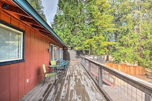 A wooden deck with a metal railing, surrounded by trees.