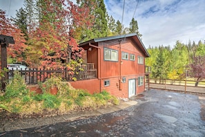 A two-story wooden cabin with a porch, surrounded by trees with autumn foliage.