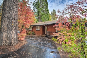A rustic cabin with a wooden deck and a driveway.