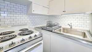 Eine Küche mit weißen Schränken, einem Kenmore Herd und einer Spüle aus Edelstahl.