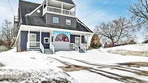 Ein zweistöckiges Haus mit Balkon, Garagentor und schneebedeckter Auffahrt.