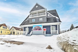 Ein zweistöckiges Haus mit Balkon, Garage und einer schneebedeckten Auffahrt.
