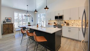 Una cocina moderna con una isla grande, taburetes de bar y un microondas.