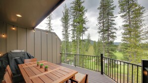 Una terraza de madera con una mesa y sillas, con vistas a una zona boscosa.