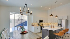 Una cocina moderna con una isla grande, armarios blancos e iluminación colgante.