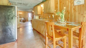 Une cuisine spacieuse dotée de meubles en bois, d’un réfrigérateur et d’un coin repas avec une table et des chaises.