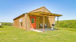 Une cabane en bois avec une porte rouge, une véranda couverte et une antenne parabolique.