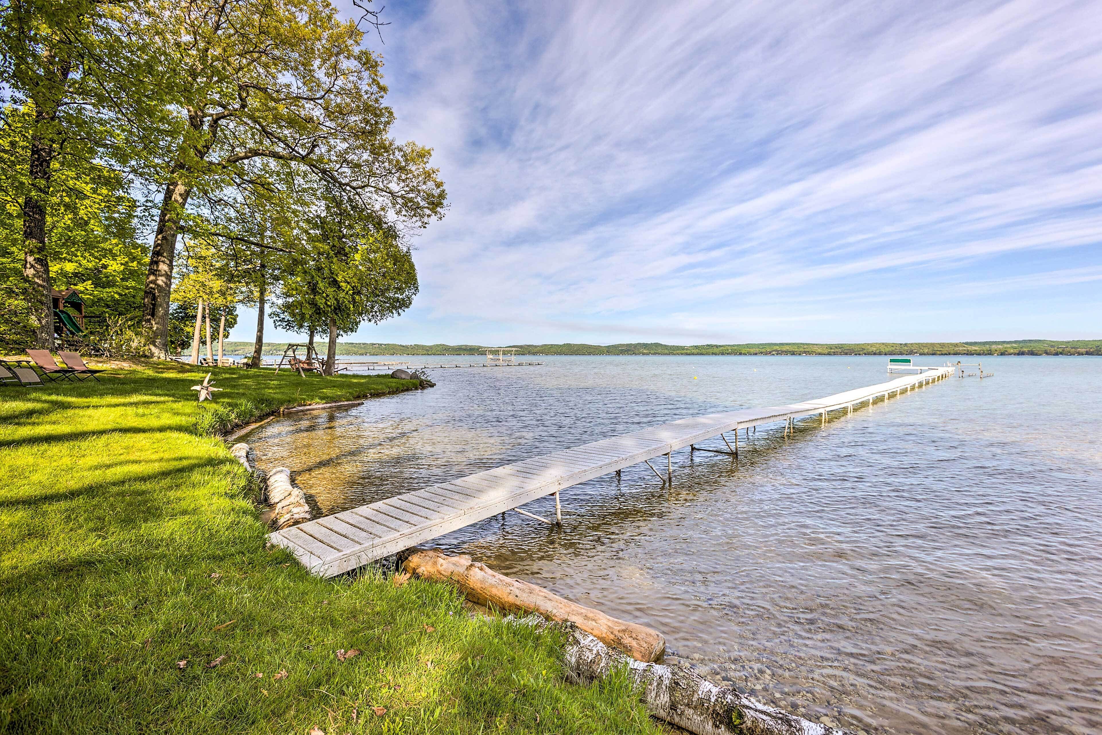 Une jetée en bois s’étendant sur un lac paisible, entourée d’une végétation luxuriante et d’arbres.