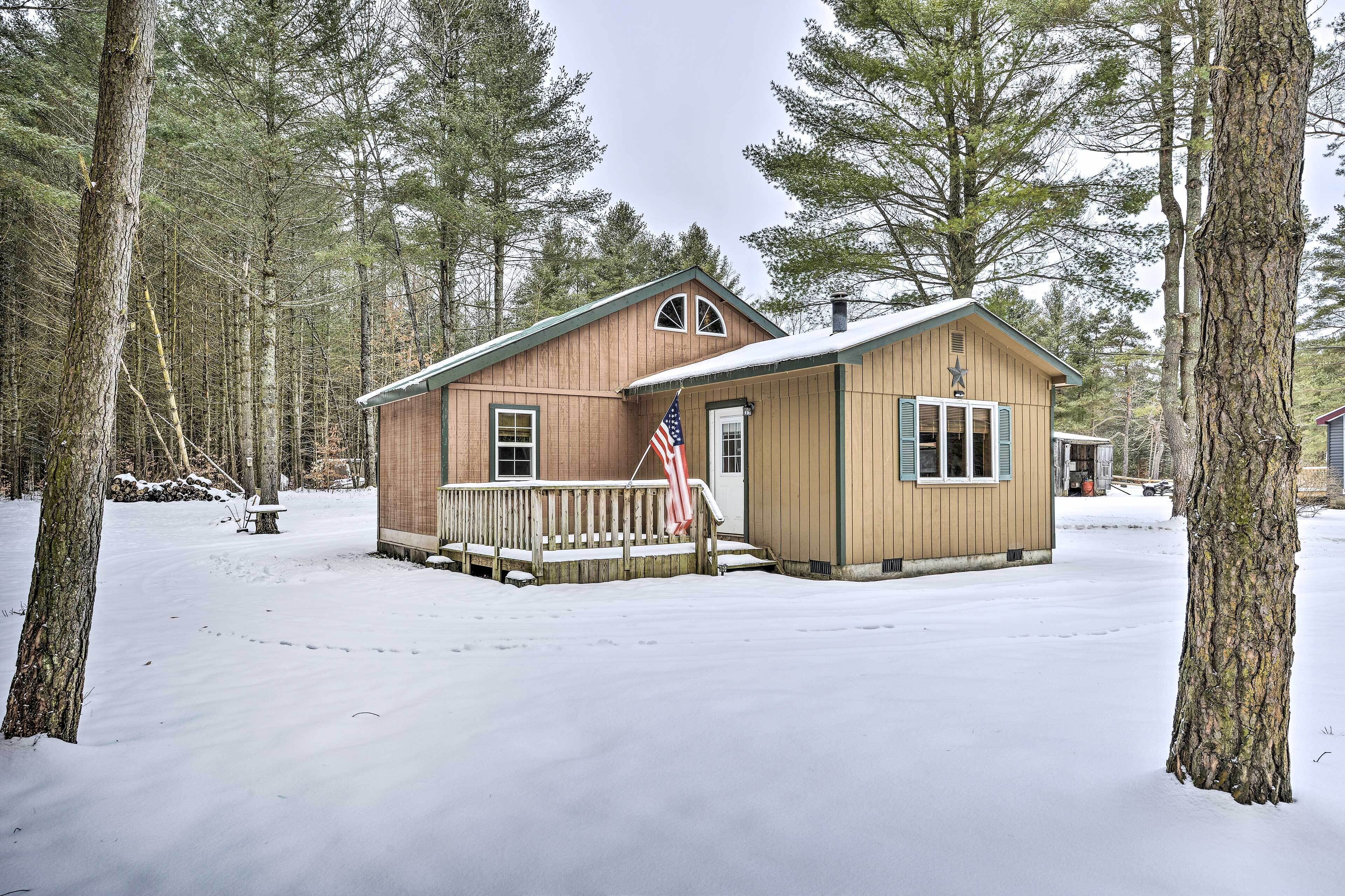 A cabin with a wooden exterior, a small porch, and an American flag.