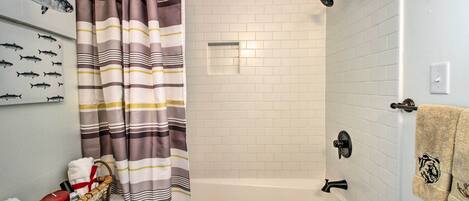 A bathroom with a bathtub, a shower, and a towel rack.