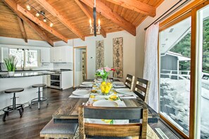 Enjoy meals in this dining area with a high ceiling and large windows offering a view of the surrounding landscape.